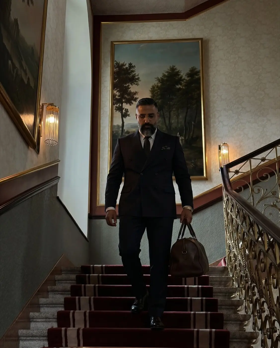 Ömer Kaya auf einer Treppe im Anzug mit Tasche